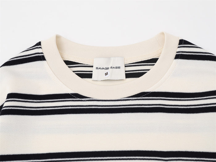 Close-up of the cream shirt’s ribbed crew neckline, inner label, and black horizontal stripe pattern