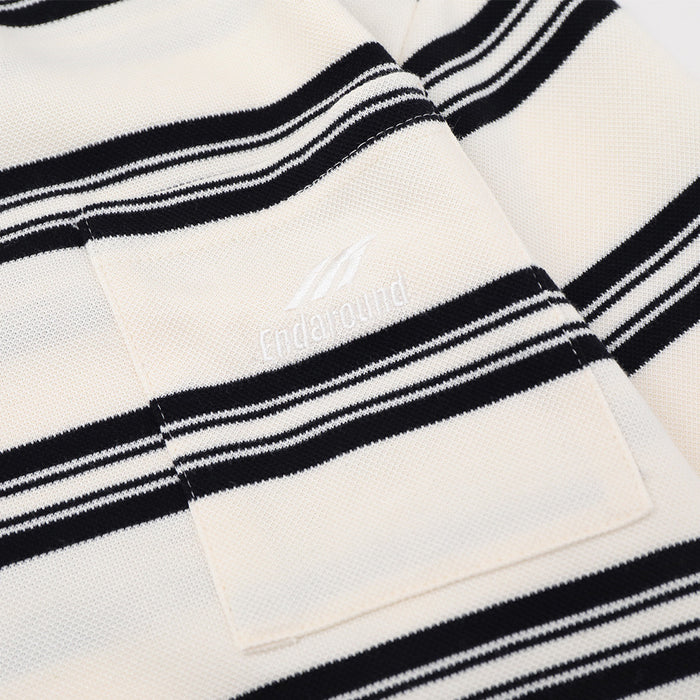 Close-up of the cream shirt’s chest patch pocket with a subtle white embroidered mark and black stripes