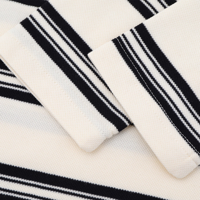 Close-up of the cream shirt sleeve cuff showing black and white striped bands and visible knit texture