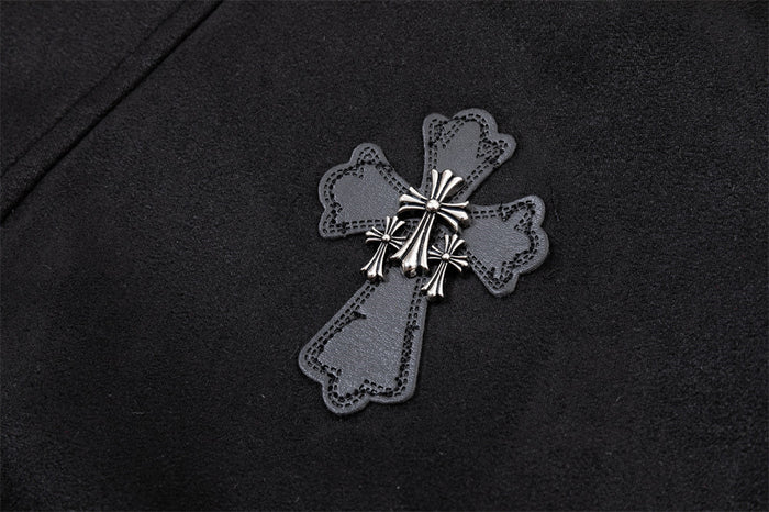 Detailed view of a gray cross applique with silver ornamental accents attached to black bomber jacket fabric
