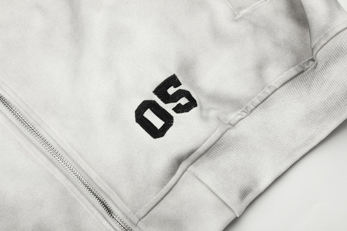 Close-up of black 05 lettering above the front pocket on the gray tie-dye hoodie