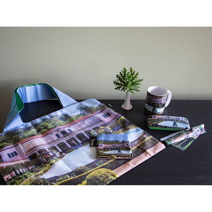Collection of Getty Villa merchandise including eyeglass case, mug and tote bag on a desk