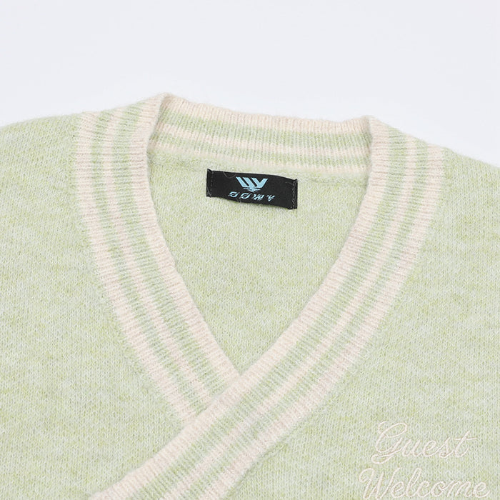 Close-up of the pale green vest's striped V-neck, ribbed knit texture, label, and embroidered chest lettering