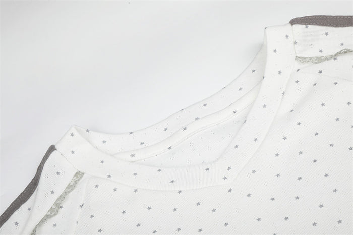 Close-up of the white V-neck collar and shoulder seam with small gray star print and side stripe detail