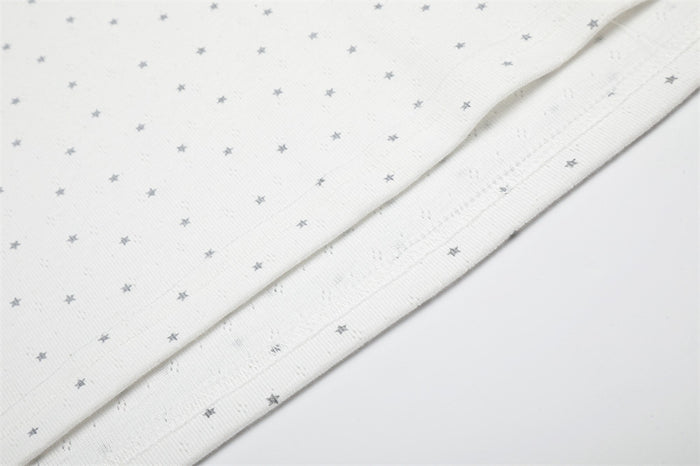 Close-up of the white shirt hem showing gray star pattern, folded edge, and fine fabric texture