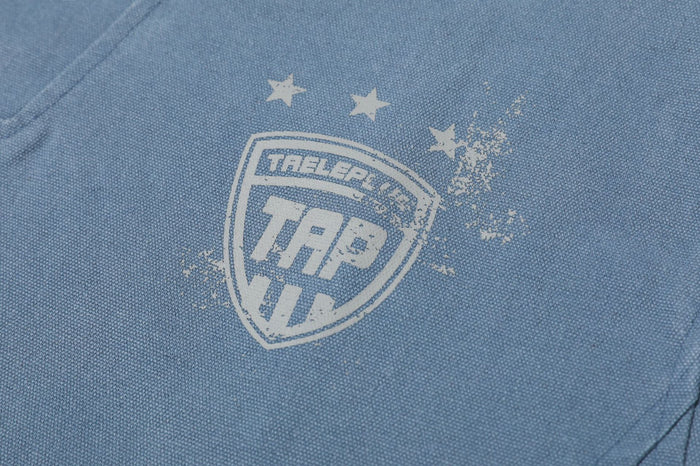 Close-up of the washed blue jacket’s distressed shield crest graphic with stars on the chest