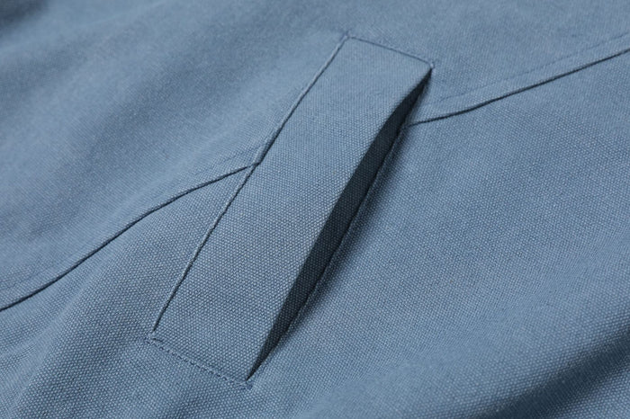 Close-up of the washed blue jacket’s angled welt pocket with visible seam stitching