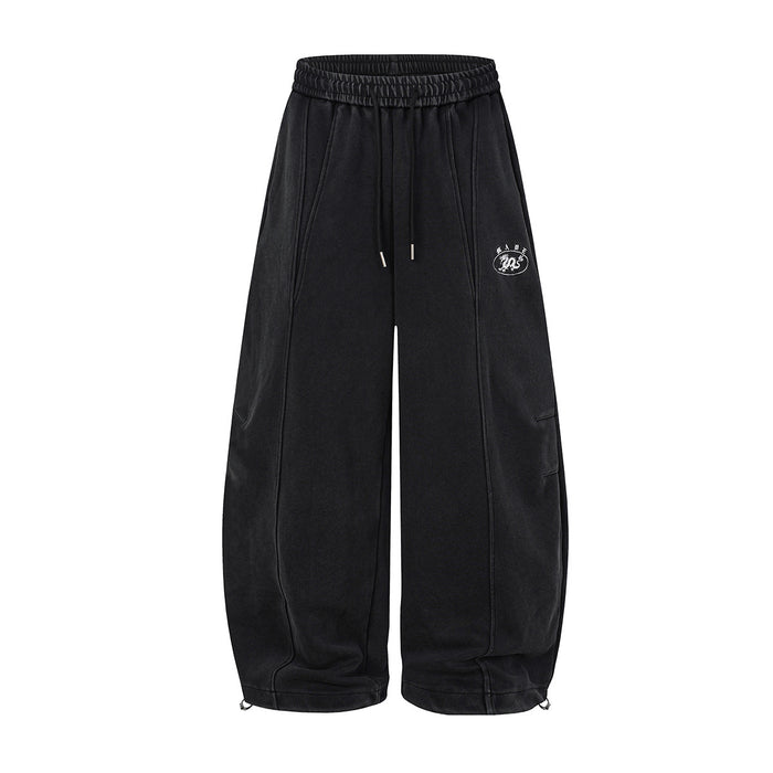 Black wide-leg sweatpants shown from the front with drawstrings, stitched panels, side pocket, and white oval dragon emblem