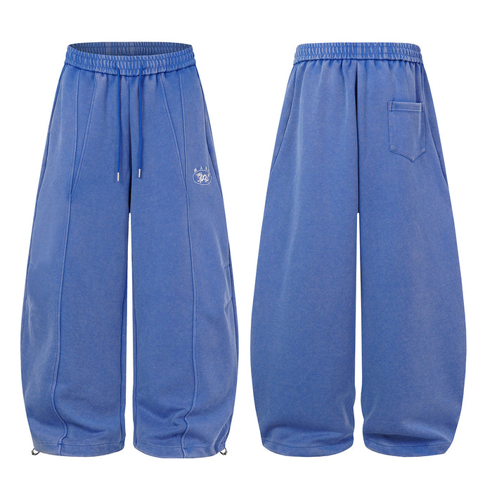 Blue wide-leg sweatpants shown front and back, featuring stitched leg panels, drawstrings, and a back pocket