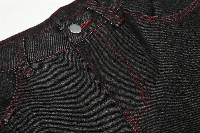 Close-up of black denim waistband, button closure, and red stitching detail