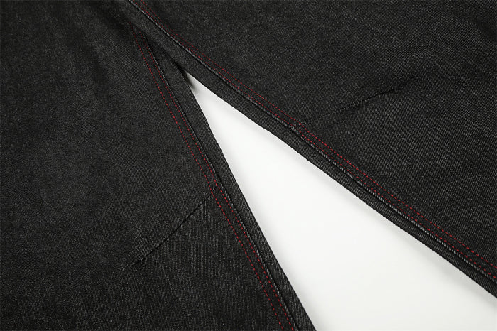 Close-up of black denim leg seam with red topstitching on curved barrel jeans