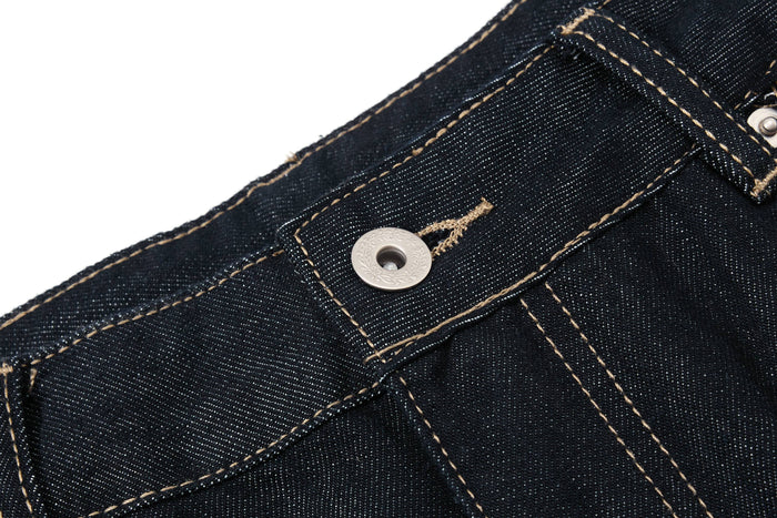 Close-up of the waistband button on dark wash denim pants with contrast stitching