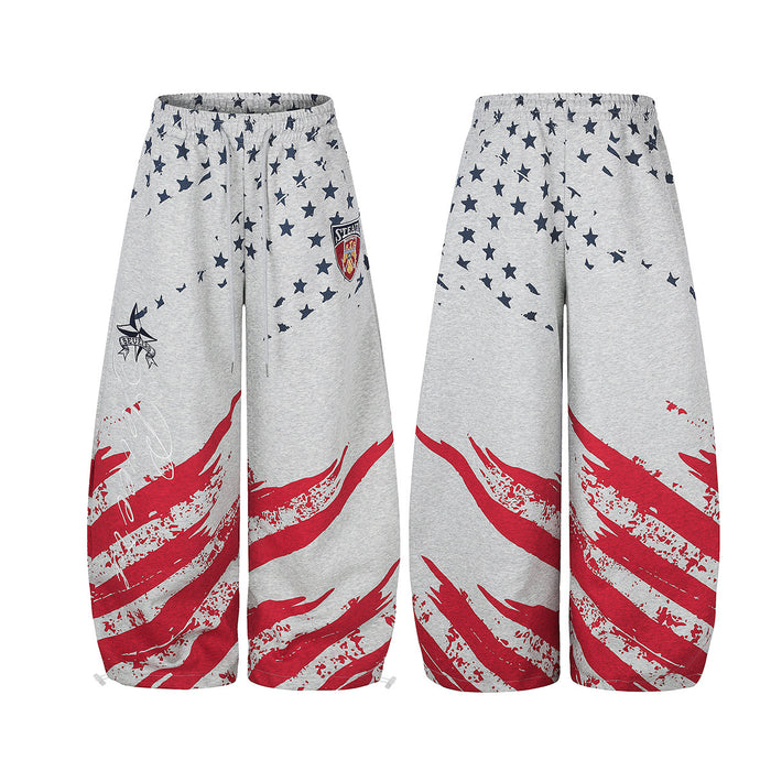 Gray wide-leg pants shown front and back with navy stars, red brushstroke stripes, and a crest patch