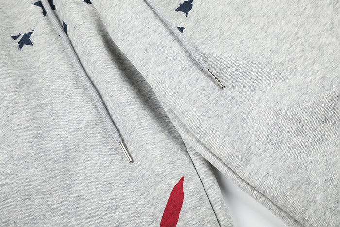 Close-up of gray pants showing the drawstring ends, center seam, and a small red print detail
