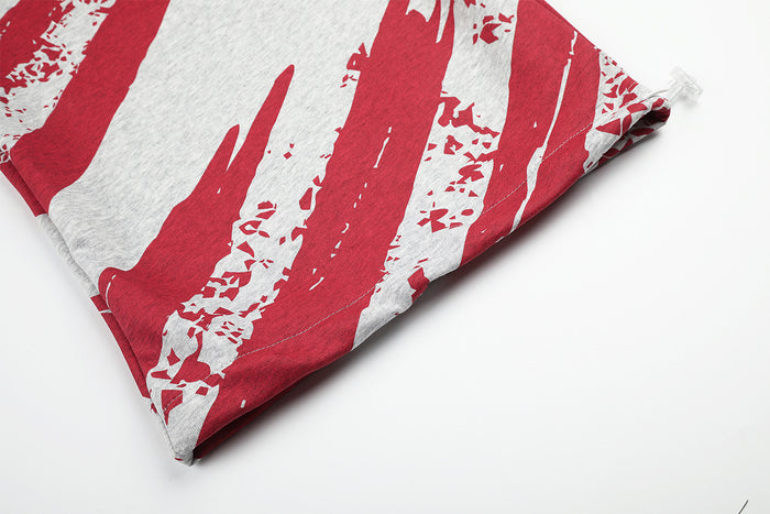 Close-up of a pant leg hem featuring bold red distressed brushstroke stripes on gray fabric