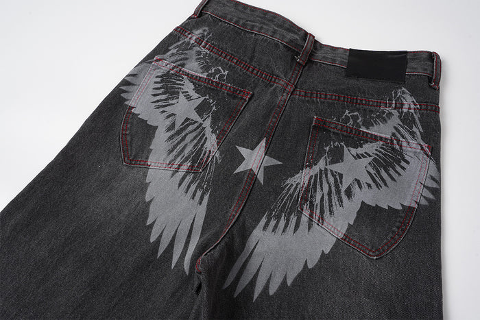 Close-up of the jeans back showing gray wing graphics, a central star, red stitching, and shaped rear pockets