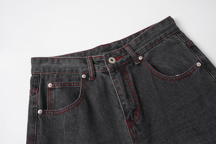 Close-up of the jeans front waistband with belt loops, button closure, zip fly, and red-stitched pockets