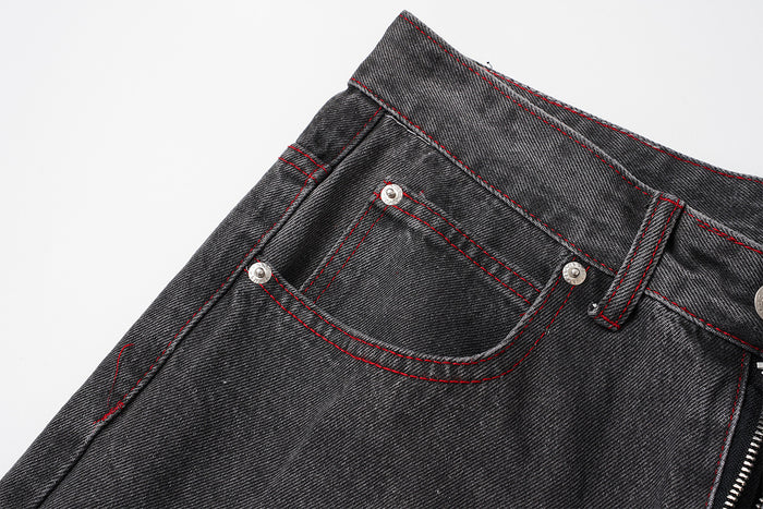 Detailed view of a front pocket on washed black denim with red contrast stitching, metal rivets, and a belt loop