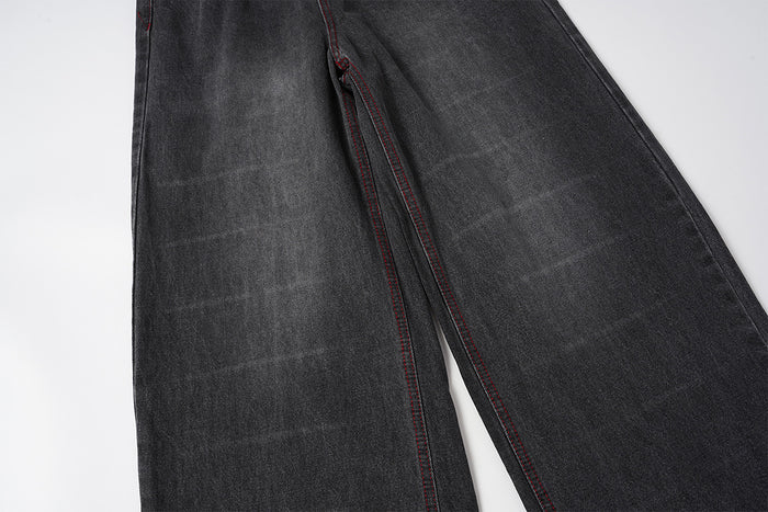 Close-up of the wide denim legs showing the inner seam and parallel red contrast stitching