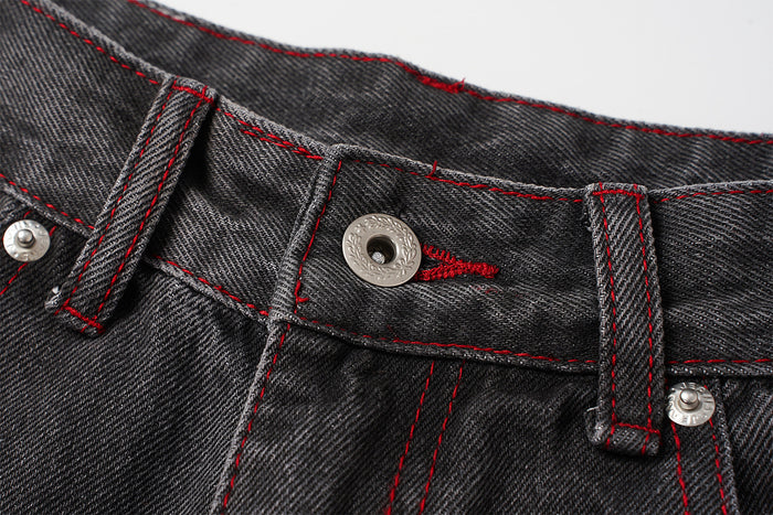 Close-up of the jeans waistband showing a metal button, buttonhole, belt loops, and red stitching