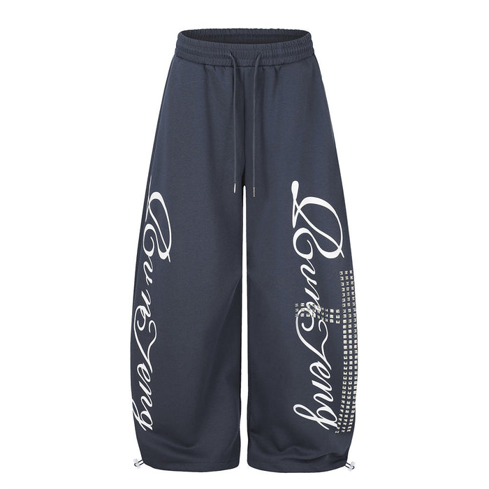 Men's oversized wide leg sweatpants in navy blue with cursive script graphic print and rhinestone cross detail on front leg p