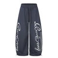 Men's oversized wide leg sweatpants in navy blue with cursive script graphic print and rhinestone cross detail on front leg p