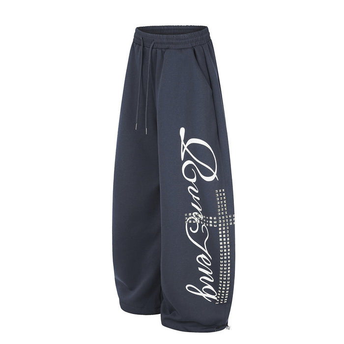 Navy wide leg sweatpants with white script graphic and rhinestone cross detail, angled front view