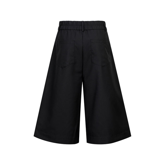 Back view of black wide-leg pleated culottes shorts with elastic waistband and patch pockets