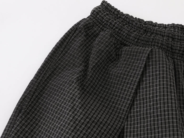 Close-up of the upper leg and waistband on black textured check pleated pants