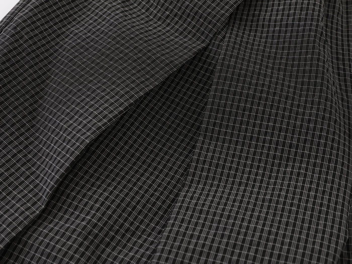Close-up of the check pattern and pleated fabric on black wide-leg pants