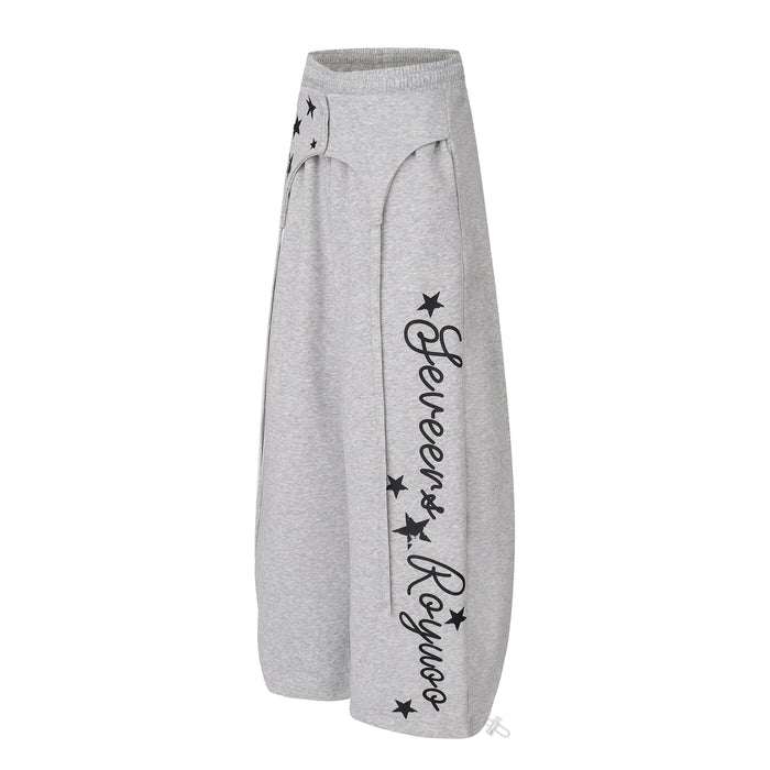 Angled gray wide-leg sweatpants with black script leg graphics, star prints, and adjustable ankle ties