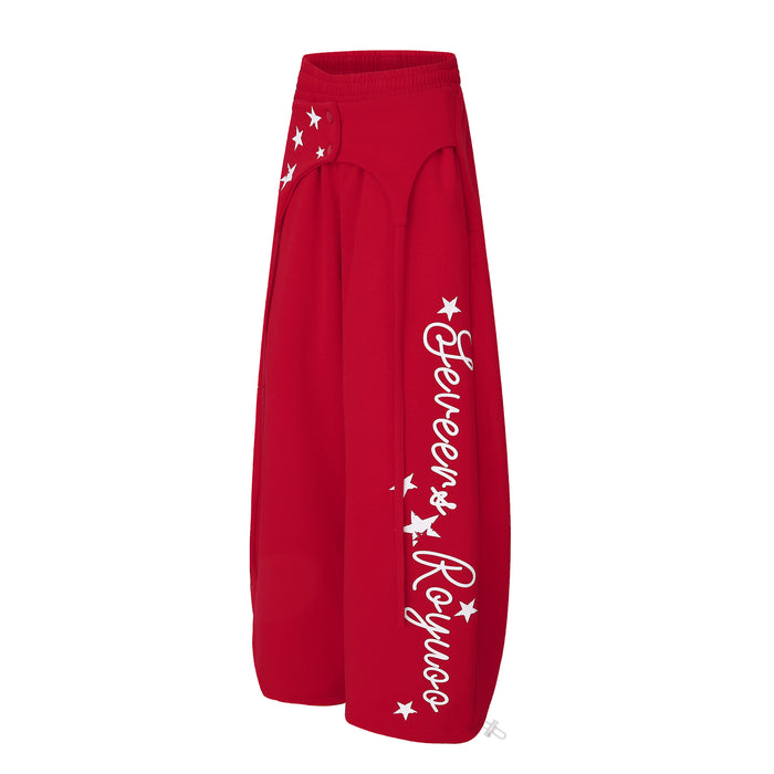 Angled red wide-leg sweatpants showing the white script graphic, star prints, and relaxed oversized legs