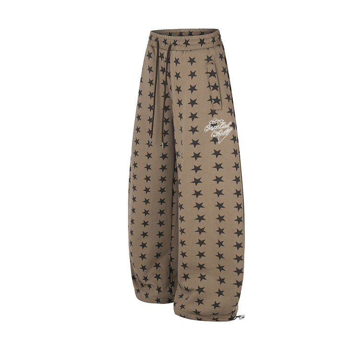 Angled view of taupe star-print wide-leg sweatpants with black drawstrings and a small side graphic