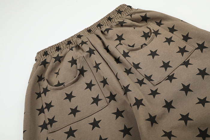 Close-up of the front curved pockets, elastic waistband, and black star pattern on taupe pants