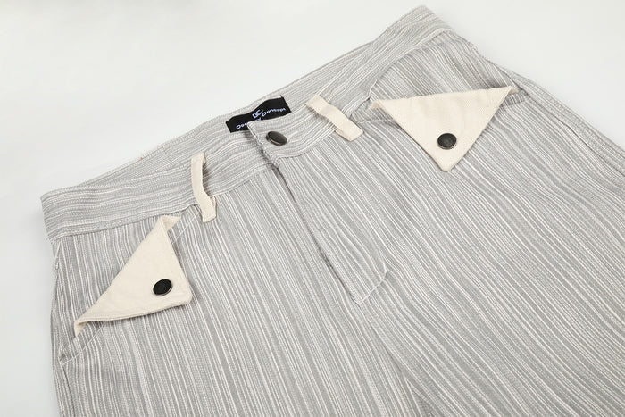 Close-up front waistband with button closure, belt loops, and triangular cream pocket flaps