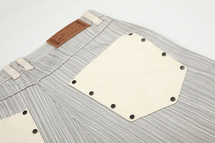 Detailed back pocket view with cream patch pocket, dark rivets, striped fabric, and brown waistband label
