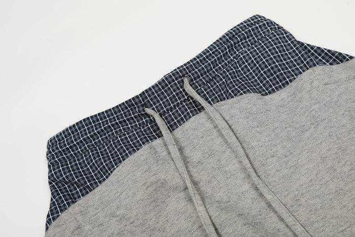 Close-up of gray sweatpants waistband with navy plaid panel and gray drawstrings