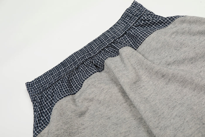 Close-up of layered waistband on gray sweatpants with navy plaid contrast panel
