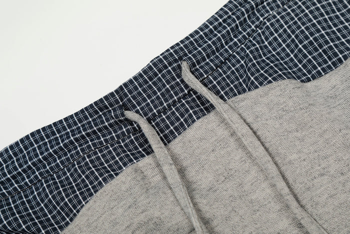 Close-up of gray drawstring and navy plaid waistband detail on sweatpants