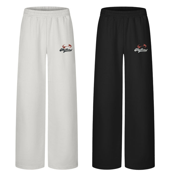 Front view of wide-leg sweatpants in white and black with elastic waistbands and embroidered thigh logos