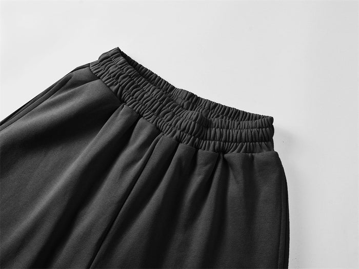 Close-up of black sweatpants showing the gathered elastic waistband and smooth fabric folds
