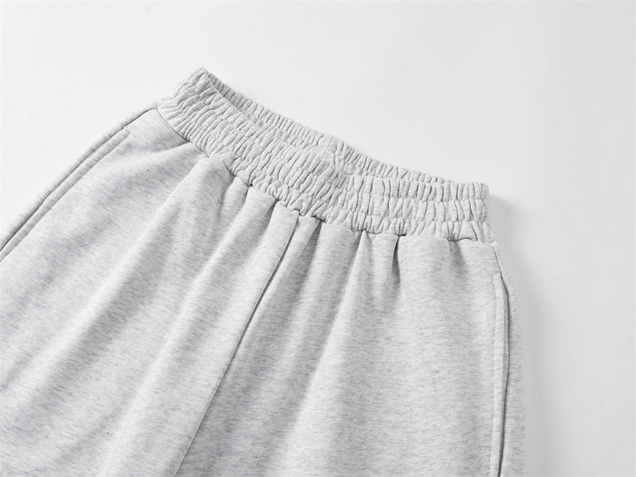 Close-up of the gray sweatpants’ gathered elastic waistband, pleated front, and soft knit fabric