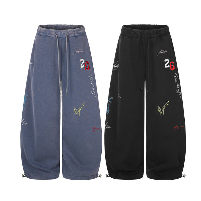 Front view of wide-leg sweatpants in blue and black with drawstrings, graffiti graphics, and number 26 embroidery