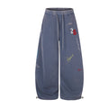 Front view of blue wide-leg sweatpants with drawstrings, multicolor graffiti graphics, and number 26 embroidery