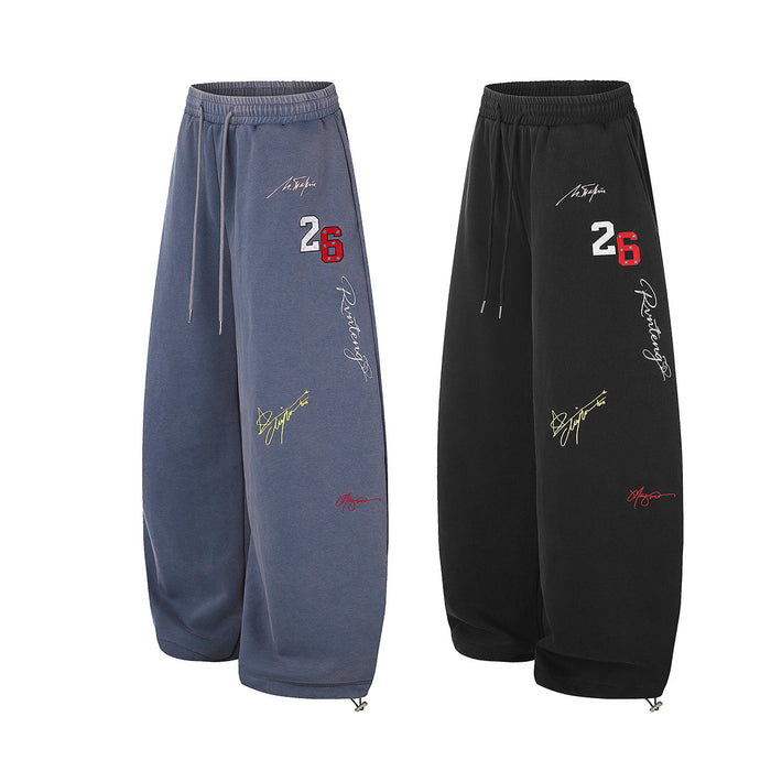 Blue and black wide-leg sweatpants shown in angled front views with drawstrings, graffiti graphics, and number 26 embroidery
