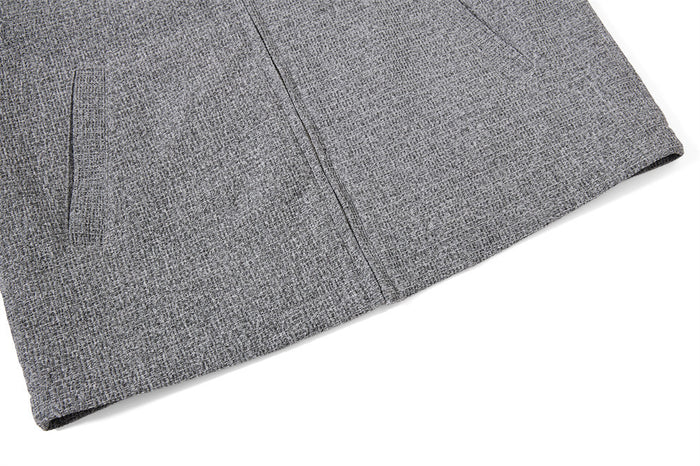 Close-up of the grey tweed jacket lower front showing the hem, zipper seam, and side pocket opening