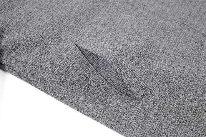 Detailed view of a slanted side pocket opening on the grey tweed jacket front