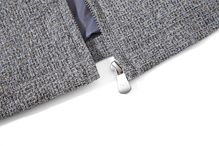 Close-up of the silver zipper pull at the bottom of the grey tweed jacket front